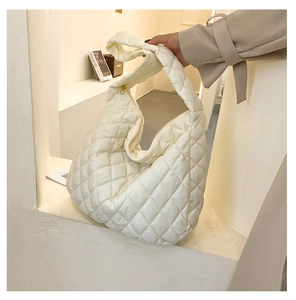 Detail of off-white quilted hobo bag featuring large diamond stitching and a gold zipper