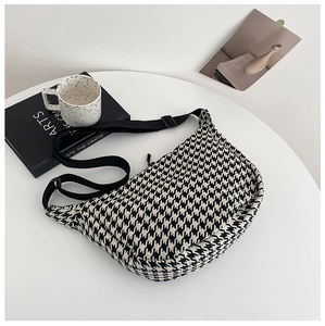 Detail of checkered woven crossbody bag with adjustable strap on a minimalist white table