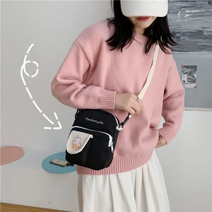 Detail of cute black canvas crossbody bag with cartoon bear patch and white strap