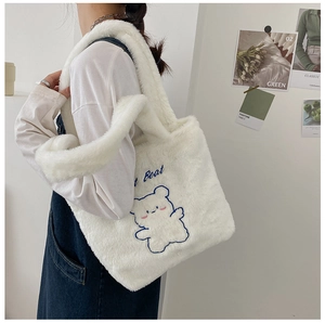 Vue détaillée du cabas en peluche blanche avec broderie ours bleu et lettres