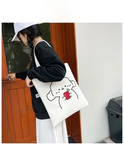 Detail shot of a white canvas tote bag with a cartoon dog illustration worn by a model