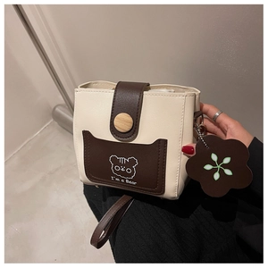 Detail of compact bucket bag with cartoon bear print and stylish wood button closure