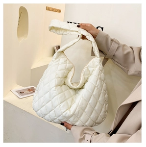 Detailed macro view of white quilted puffer shoulder bag with soft nylon texture