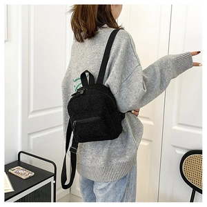 Close-up of black fleece mini backpack with adjustable straps on a person's back