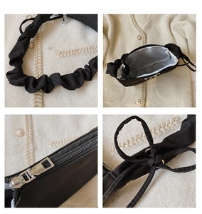 Detail view of black pleated bag featuring adjustable bow knots and silver zipper hardware