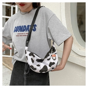 Detail of cow print nylon crossbody bag with adjustable strap and cute cow pendant