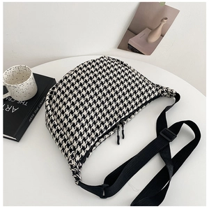 Detail of black and white houndstooth crossbody bag with adjustable nylon strap and zippers