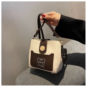 Detail of color-block bucket bag with cute cartoon bear and rustic wooden buckle
