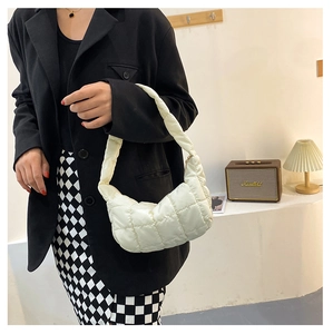 Close-up of white quilted nylon underarm bag with puffy texture and wide handle