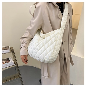 Detail of white quilted cloud bag featuring soft padded texture and wide shoulder strap