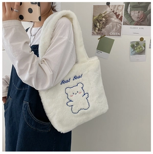Détail du sac fourre-tout en peluche blanche avec broderie ours bleu et texture douce