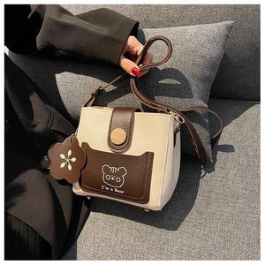 Detail of color-block bucket bag featuring a cartoon bear print and decorative wooden button