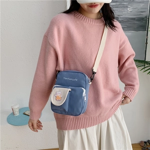 Detail of blue canvas crossbody bag with cute bear patch and logo embroidery