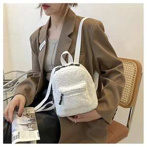Detailed view of mini white faux shearling backpack with thin straps worn by a model