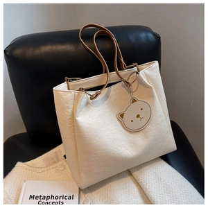 Detailed relief embossing on cream tote bag featuring cats and hearts on leather