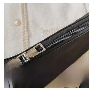 Close-up of smooth silver metal zipper on minimalist black canvas crossbody bag