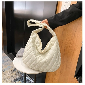 Detailed close-up of a cream quilted tote bag with rhombus stitching on a white table