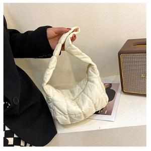 Detail view of white quilted dumpling bag with ruched handle and golden zipper