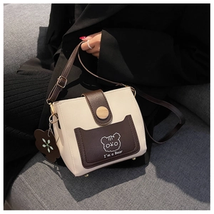 Detail of crossbody bucket bag featuring embroidered bear and wooden button closure