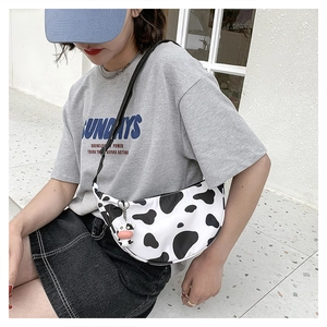 Close-up of cow print crescent bag featuring a cute cow plush pendant and nylon fabric