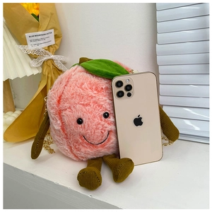 Detailed view of peach-shaped plush bag with metal chain beside an iPhone for size scale