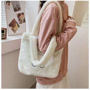 Détail du sac fourre-tout en peluche blanche avec un adorable motif de sourire brodé