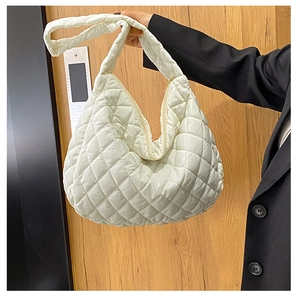 Macro shot of white quilted shoulder bag showing fine diamond stitching and puffed texture