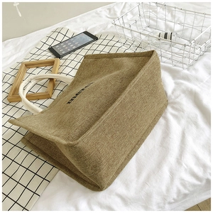 Detail of jute tote bag showing high-quality woven texture and merci print on side