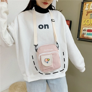 Detail of light pink canvas crossbody bag featuring cute candy patches and adjustable strap