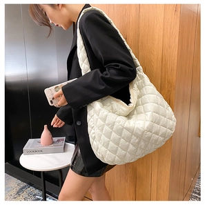 Detail view of beige quilted crossbody bag featuring soft cloud pleats and large capacity