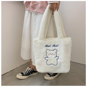 Gros plan du sac fourre-tout en peluche blanche avec broderie ours bleu et texte