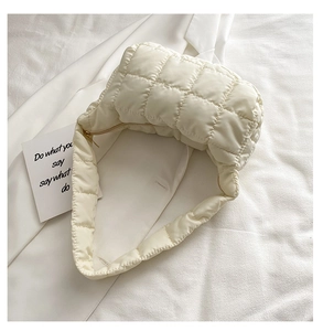 Detail of off-white quilted puffer bag featuring soft texture and smooth zipper closure