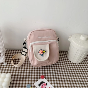 Detail of pink canvas crossbody bag with rainbow lollipop patch and front pocket