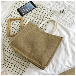 Top view of a large jute tote bag with thick white rope handles on a checkered fabric background