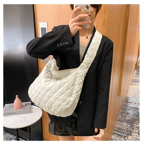 Close-up of beige quilted crossbody bag showing soft puffer texture and spatial design