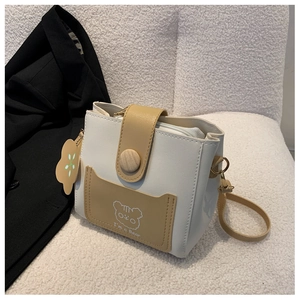 Detail shot of mini bucket bag showing wooden button and cartoon bear print on beige leather