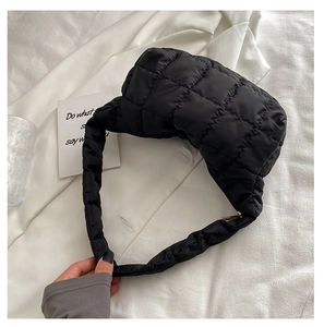 Close-up of black quilted shoulder bag featuring glossy nylon fabric and gold zipper detail