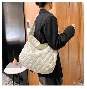 White quilted puffer tote bag shown on shoulder in a minimalist indoor lifestyle setting