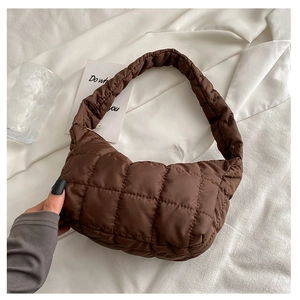 Detail of dark brown quilted puffer bag with rhombic stitching on soft fabric