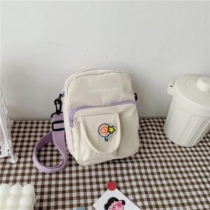 Detail of cream canvas crossbody bag with purple zipper and adjustable shoulder strap