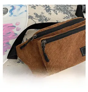 Detailed close-up of brown corduroy chest bag featuring a smooth double zipper and letter patch