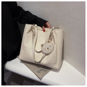 Close-up of embossed bear and cloud patterns on off-white faux leather tote bag