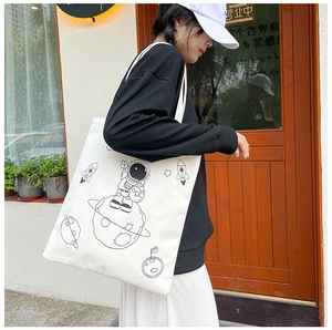 Detailed shot of large white canvas tote bag with astronaut illustration on model