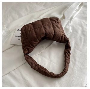 Detail of a dark brown quilted shoulder bag with soft nylon padding and broad strap