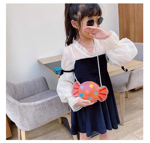 Détail du sac bandoulière orange en forme de bonbon avec pois colorés sur un enfant
