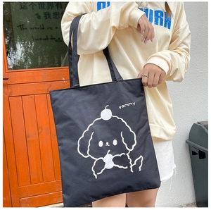 Detail of black canvas tote bag featuring a white cartoon dog and yammy print