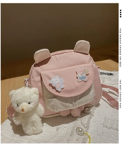 Detail of a pink and white crossbody bag with cute bear ears and plush bear charm