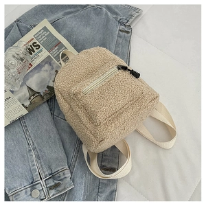 Detail shot of beige faux fur mini backpack on denim jacket with textured lamb wool fabric
