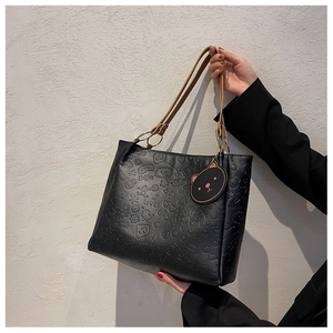 Detail of black PU tote bag with cartoon embossing and a cute bear bag charm accessory