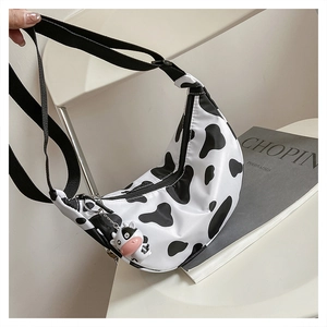 Detail of half-moon nylon crossbody bag with cow print and cute plush cow keychain charm